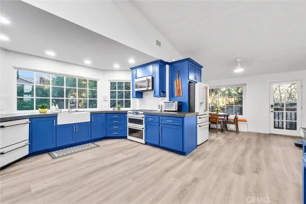 a kitchen with stainless steel appliances kitchen island granite countertop a stove a refrigerator a sink with wooden cabinets and wooden floor