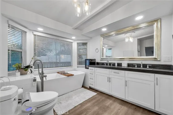 a bathroom with a granite countertop sink mirror vanity bathtub and a toilet