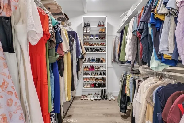 a view of walk in closet with clothes and shoes