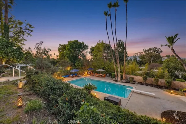 a view of a backyard with couches under an umbrella