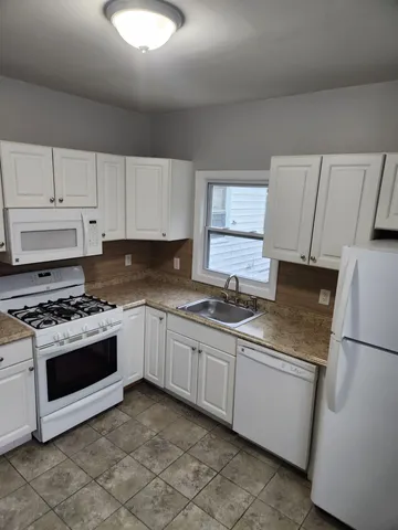 a kitchen with granite countertop a sink stove and refrigerator