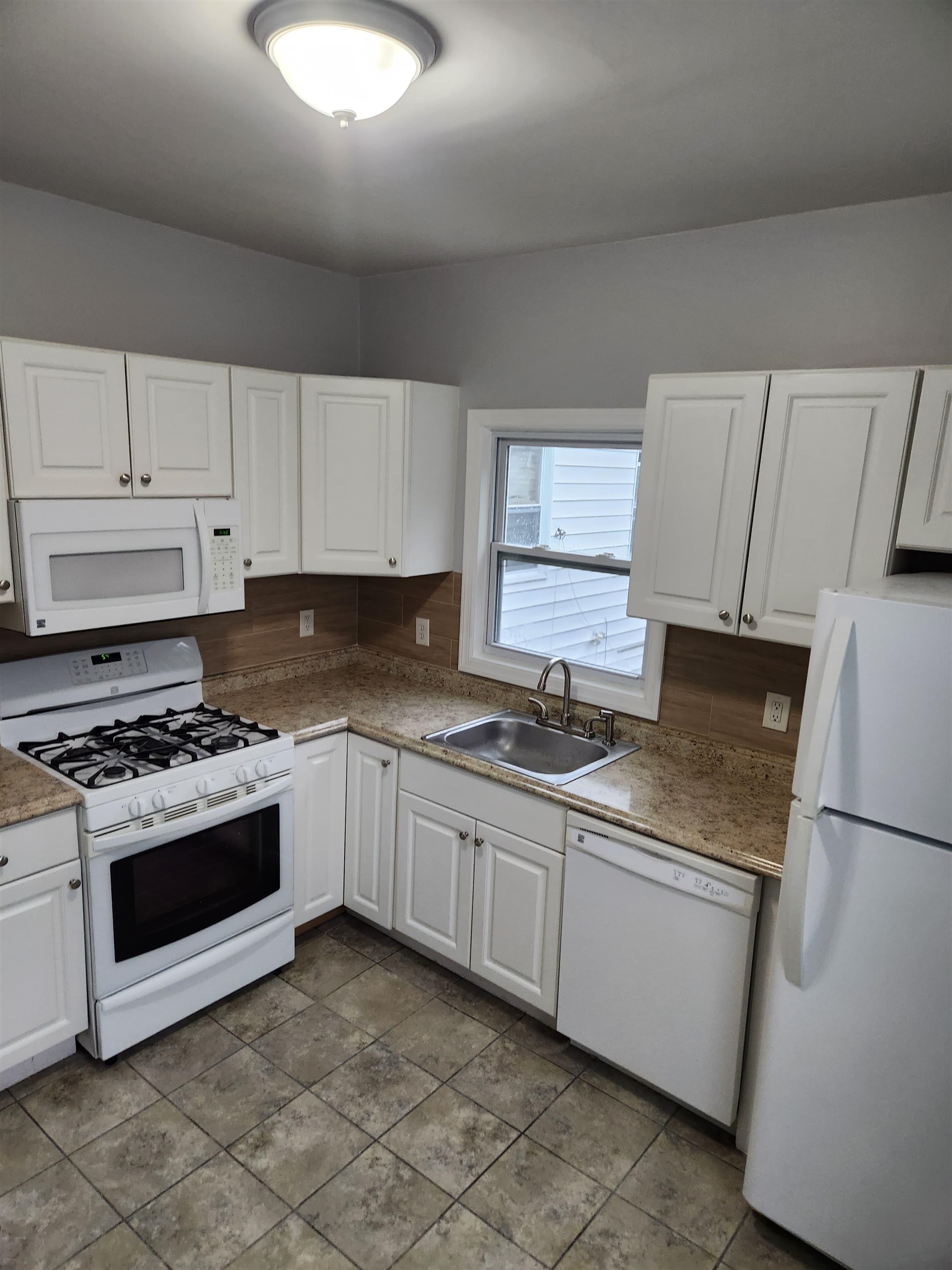 a kitchen with granite countertop a sink stove and refrigerator
