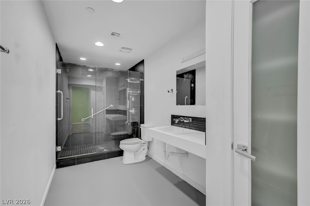 640 North Racetrack Road Henderson, NV 89015 - Photo 50 of 65 A modern bathroom features a spacious glass-enclosed shower, a sleek wall-mounted sink, and bright recessed lighting.