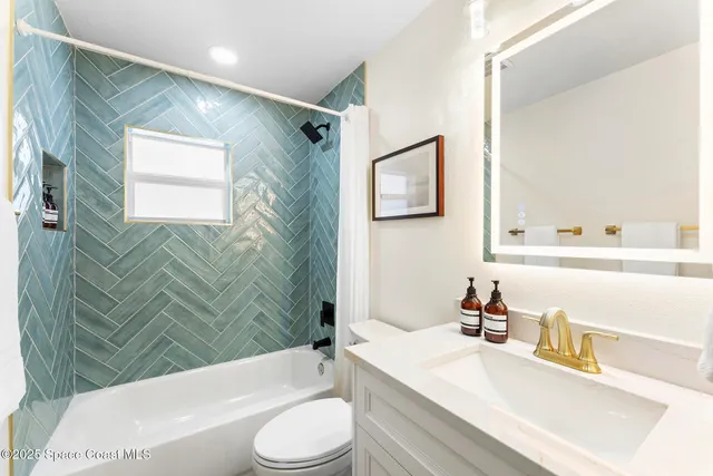 a bathroom with a granite countertop bathtub sink vanity mirror and toilet