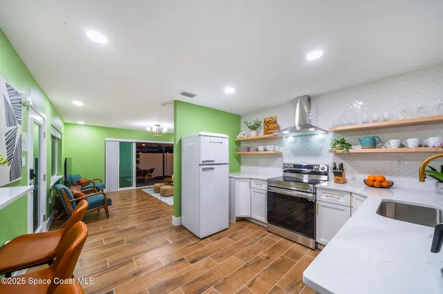 a kitchen with stainless steel appliances a stove a refrigerator a sink dishwasher and a refrigerator with wooden floor