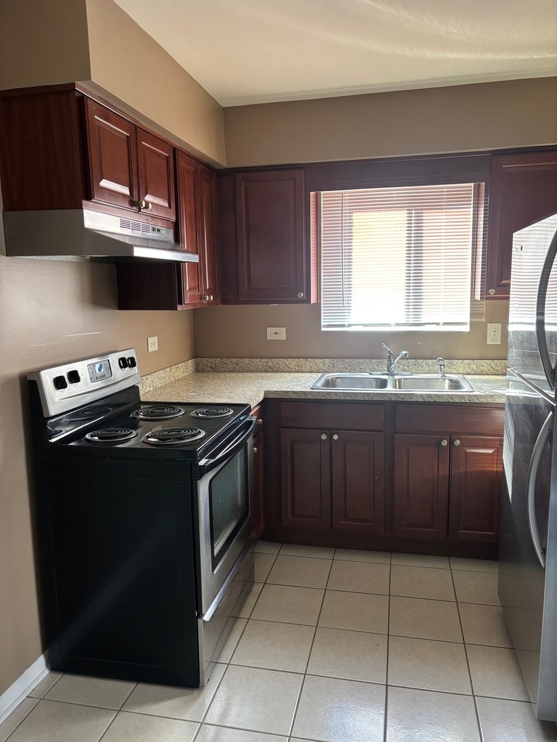 6323 West 64th Place, Unit 1D Chicago, IL 60638 - Photo 5 of 16 a kitchen with stainless steel appliances granite countertop a stove a sink and a microwave