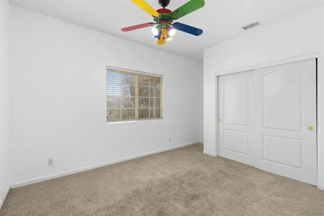 an empty room with closet and fan