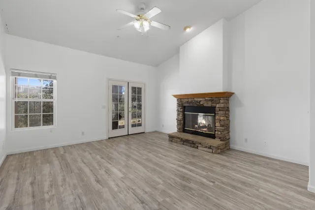 a view of an empty room with wooden floor fireplace and a window