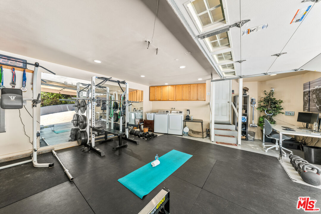 3940 Mandeville Canyon Road Los Angeles, CA 90049 - Photo 20 of 54 a living room with furniture a large window and gym equipment