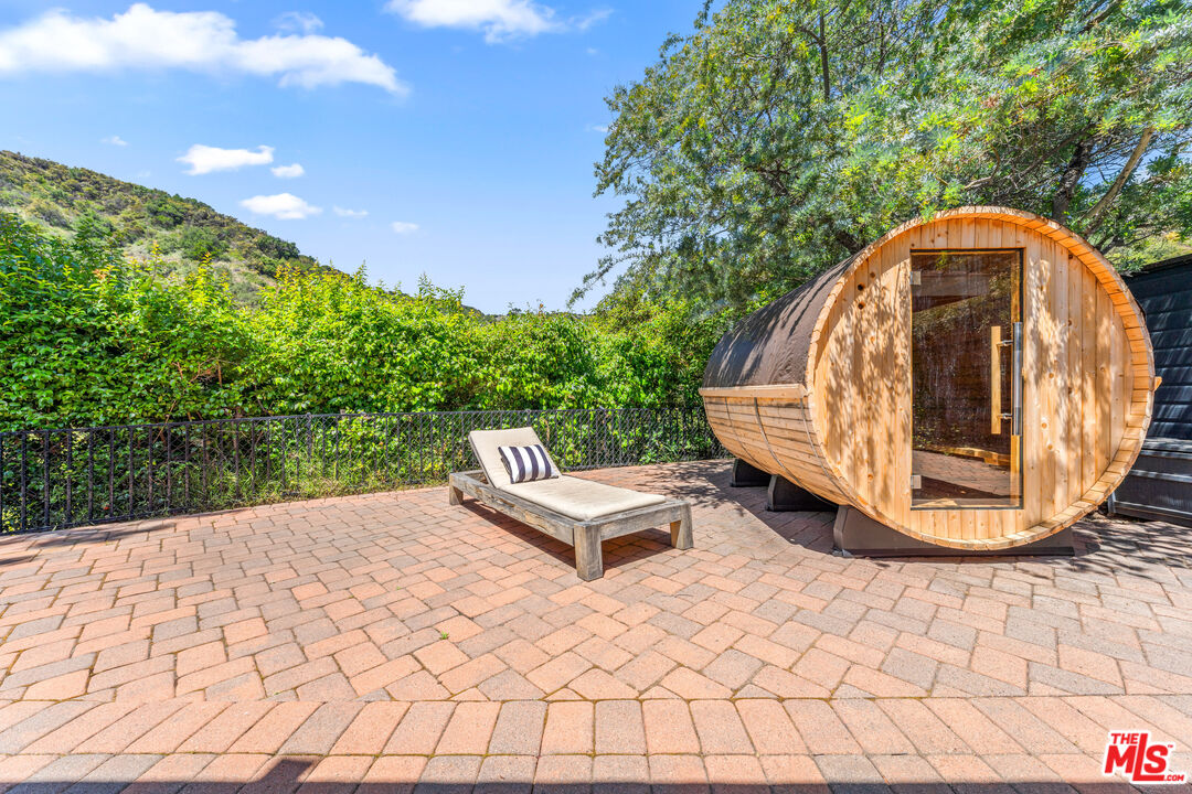 3940 Mandeville Canyon Road Los Angeles, CA 90049 - Photo 23 of 54 a backyard of a house with table and chairs
