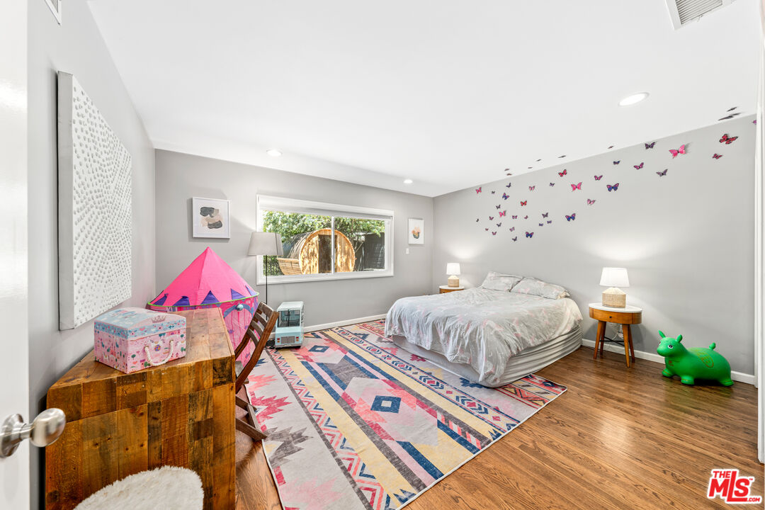 3940 Mandeville Canyon Road Los Angeles, CA 90049 - Photo 33 of 54 a spacious bedroom with a bed and wooden floor