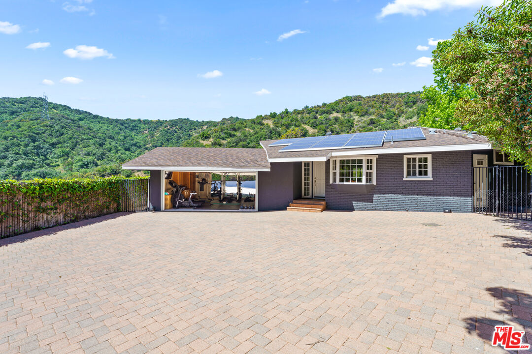 3940 Mandeville Canyon Road Los Angeles, CA 90049 - Photo 48 of 54 a front view of a house with yard and green space