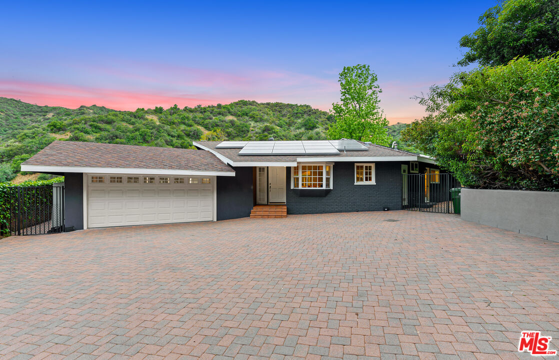 3940 Mandeville Canyon Road Los Angeles, CA 90049 - Photo 49 of 54 a front view of a house with a yard and a garage