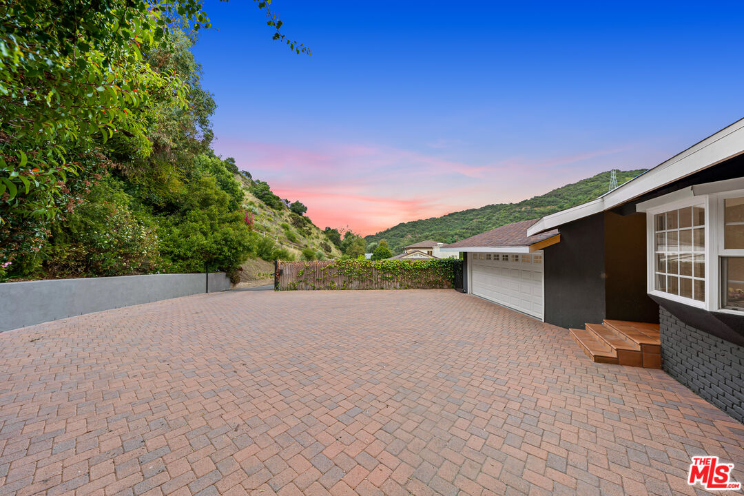3940 Mandeville Canyon Road Los Angeles, CA 90049 - Photo 52 of 54 a view of a house with a yard