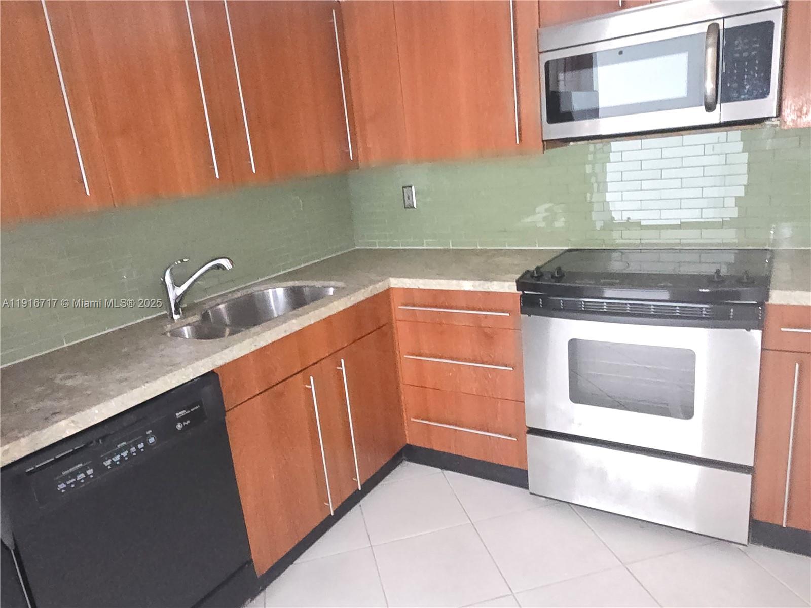 1775 Washington Avenue, Unit 4G Miami Beach, FL 33139 - Photo 12 of 44 a kitchen with granite countertop a sink stove and cabinets