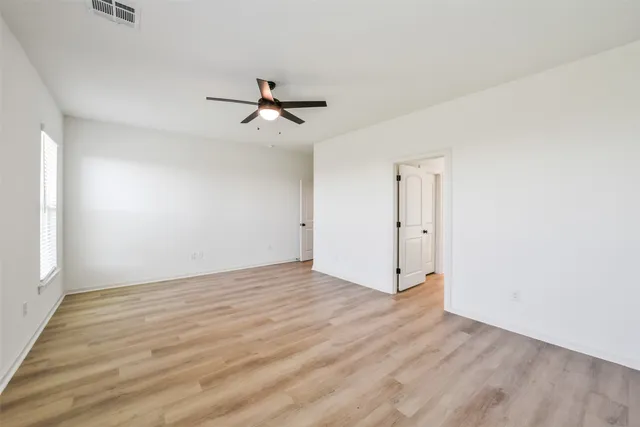 a view of empty room with wooden floor and ceiling fan