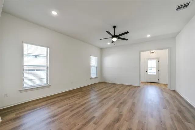 an empty room with wooden floor and windows