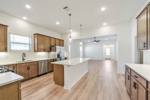 a large kitchen with stainless steel appliances lots of counter space and wooden floor