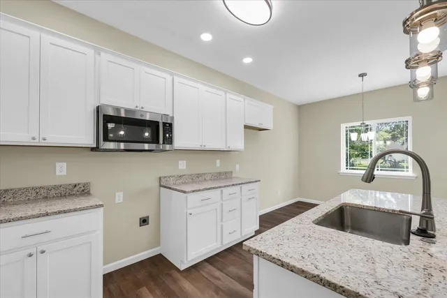 a kitchen with granite countertop white cabinets and a stove top oven