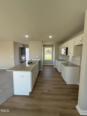 a large white kitchen with wooden floor and a sink
