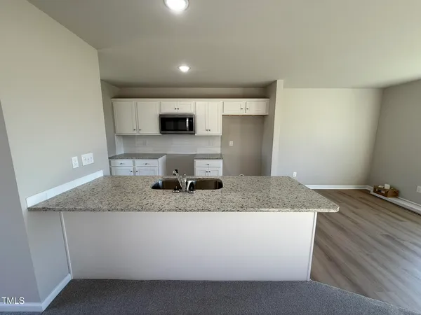 a kitchen with kitchen island granite countertop a sink a counter top space and cabinets