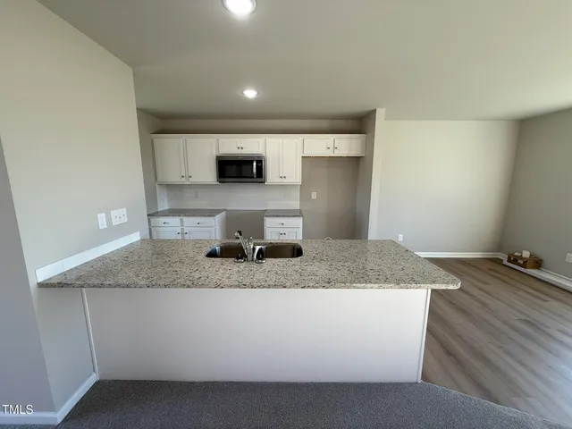 a kitchen with kitchen island granite countertop a sink a counter top space and cabinets