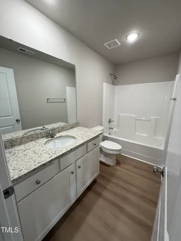 a bathroom with a granite countertop sink a toilet a large mirror and shower