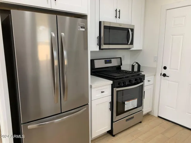 a kitchen with stainless steel appliances granite countertop a refrigerator a stove and microwave