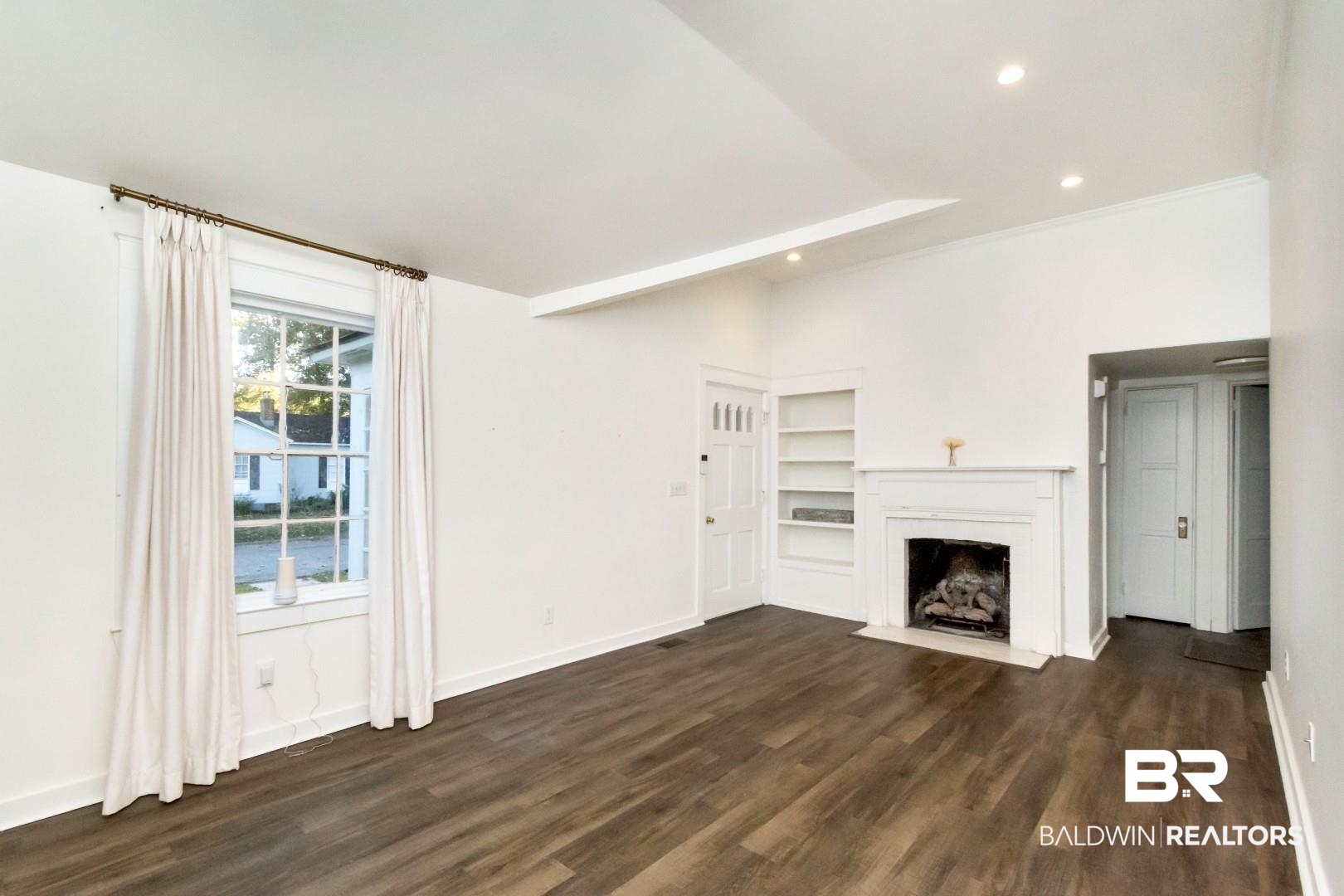16 Princess Anne Road Mobile, AL 36608 - Photo 4 of 40 Unfurnished living room with a fireplace with flush hearth, dark wood finished floors, recessed lighting, beam ceiling, and a water view