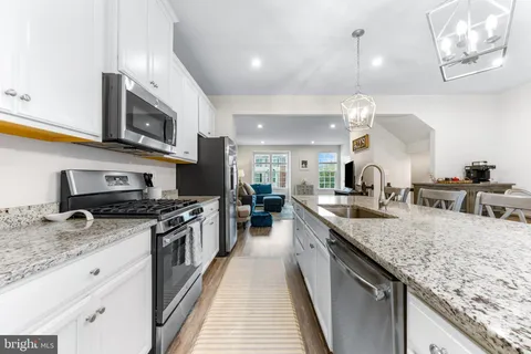 a large kitchen with stainless steel appliances granite countertop a lot of counter space and wooden floor