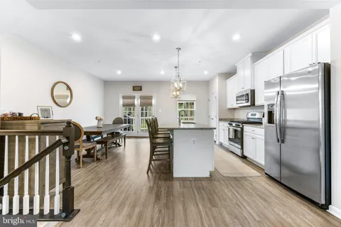 an open kitchen with wooden floor and stainless steel appliances