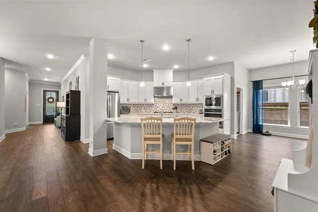 a kitchen with stainless steel appliances kitchen island wooden floors stove and white cabinets