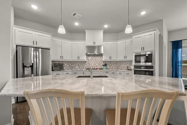 a kitchen with kitchen island a stove a refrigerator and a sink