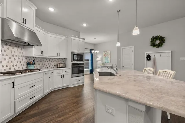 a kitchen with stainless steel appliances kitchen island granite countertop a stove and a sink