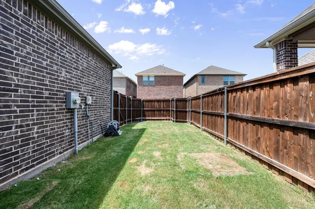 a view of backyard with brick wall and a large tree