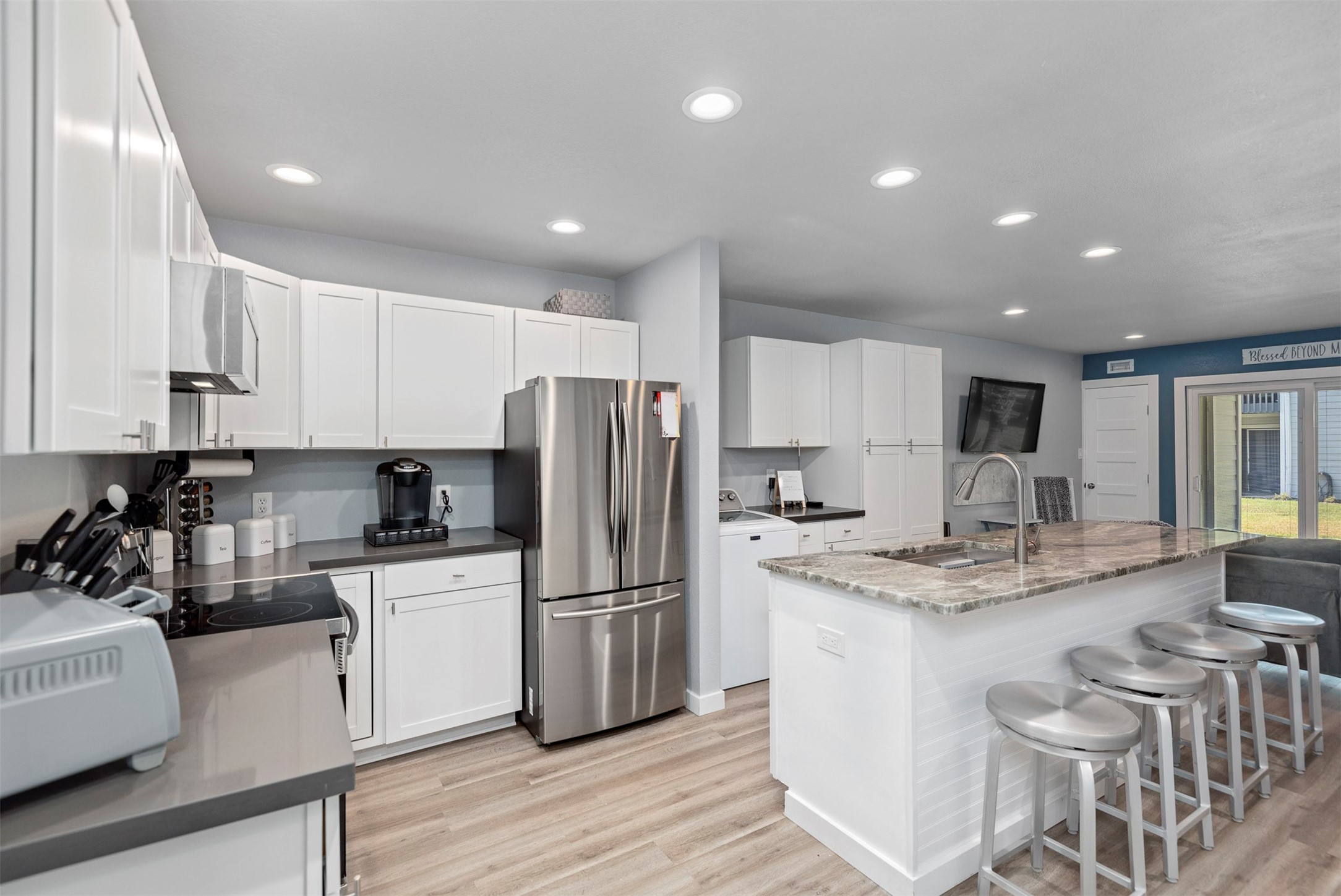 a kitchen that has a lot of white cabinets and stainless steel appliances