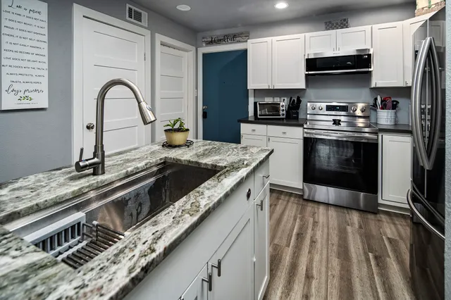 a kitchen with stainless steel appliances granite countertop a stove a sink and a microwave