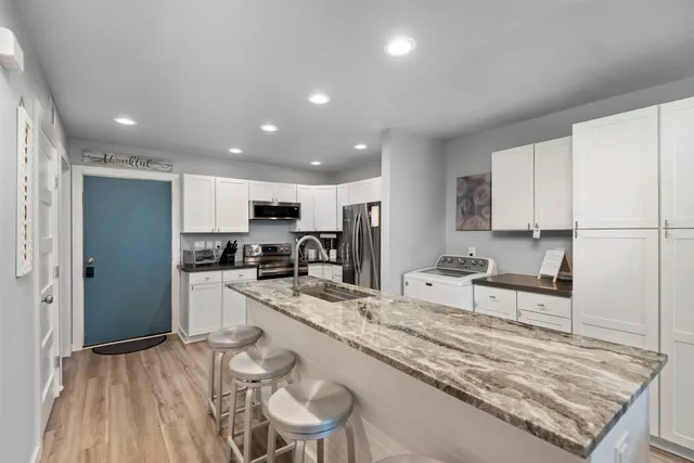 a large kitchen with kitchen island a sink stove and white cabinets