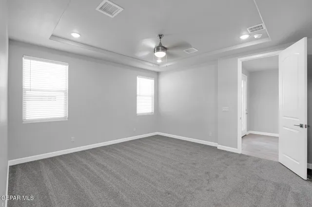 an empty room with windows and ceiling fan