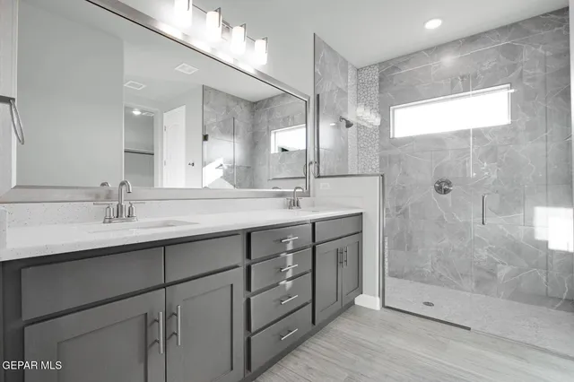 a bathroom with a double vanity sink mirror and shower