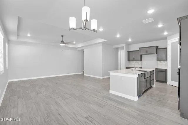 a large kitchen with kitchen island a stove a sink dishwasher a refrigerator and white cabinets with wooden floor