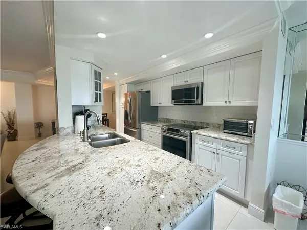 a kitchen with stainless steel appliances kitchen island granite countertop a sink stove and refrigerator