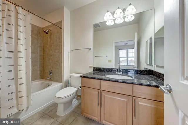 a bathroom with a granite countertop sink a toilet a mirror and shower