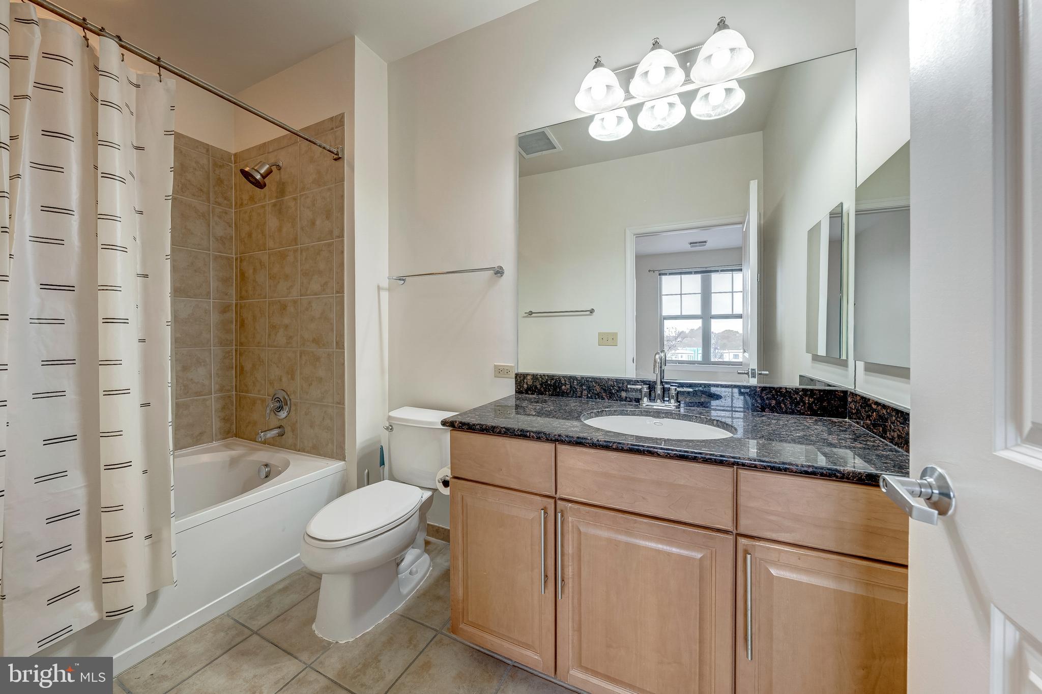 11770 Sunrise Valley Drive, Unit 321 Reston, VA 20191 - Photo 16 of 36 a bathroom with a granite countertop sink a toilet a mirror and shower