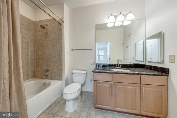 a bathroom with a granite countertop sink a toilet a mirror a bathtub and shower