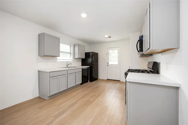 a kitchen with a stove top oven a sink a refrigerator and cabinets