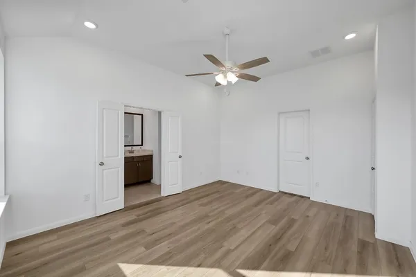a view of empty room with wooden floor and ceiling fan