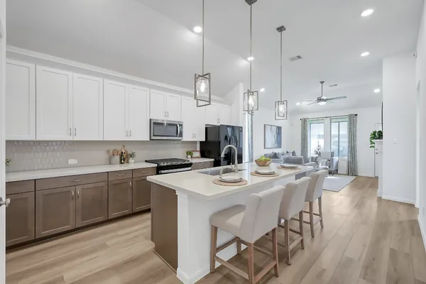 a kitchen with stainless steel appliances kitchen island granite countertop a sink a stove a dining table and chairs