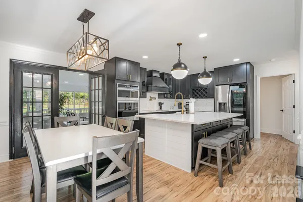 a kitchen with stainless steel appliances a dining table chairs and wooden floor