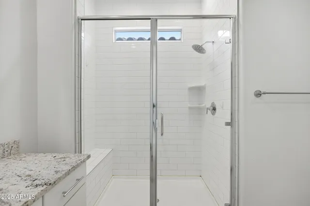 a bathroom with a granite countertop shower and a mirror